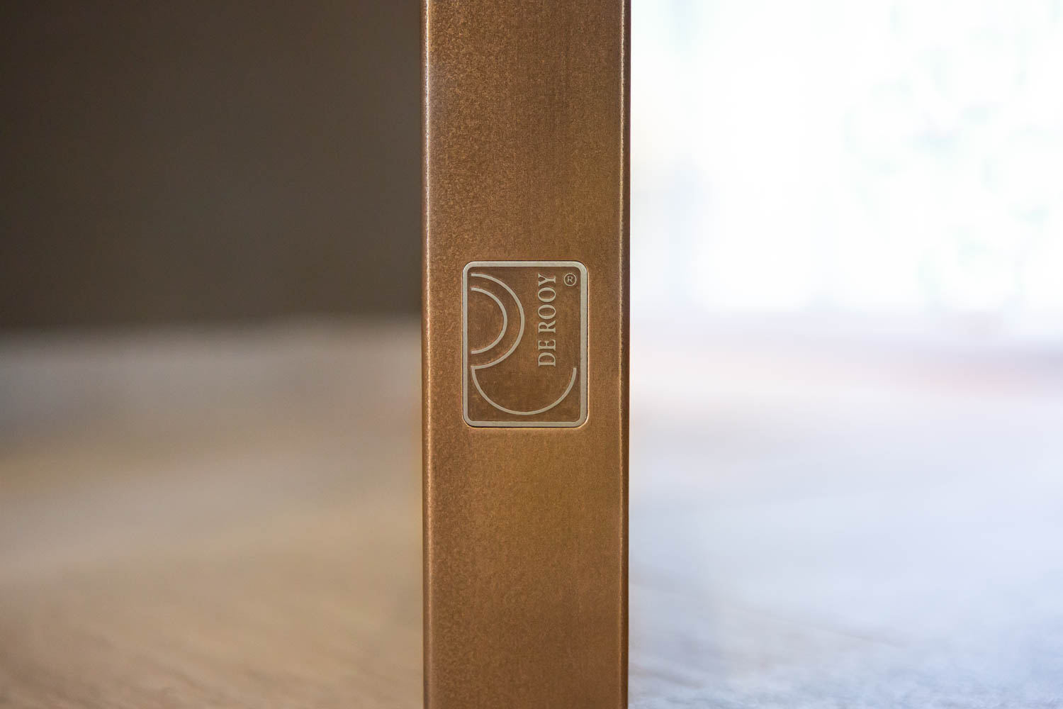 Logo van De Rooy op een bronzen stalen deur, symbool van vakmanschap.